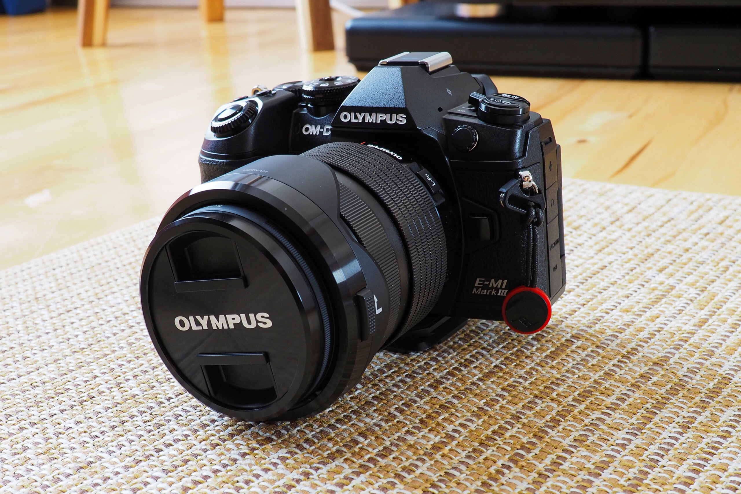 オリンパスOM-D E-M1 Mark IIIにレンズを付けて床のラグに置いた状態