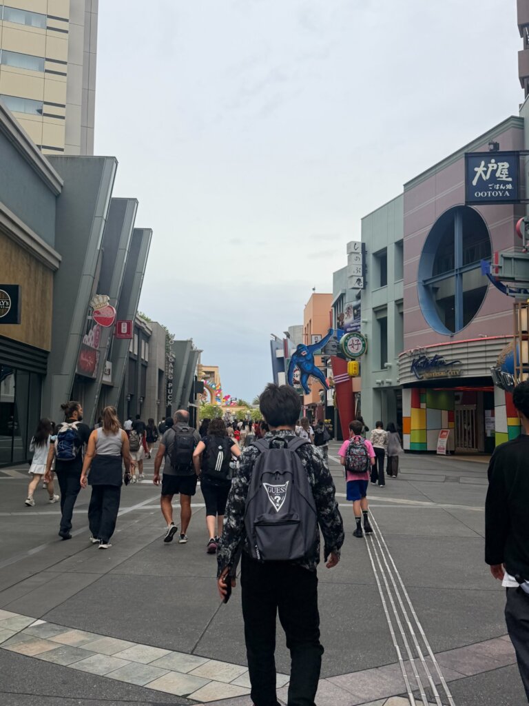 リュックを背負った人たちが、店の並ぶ通りを奥のゲートの方へ歩いている
